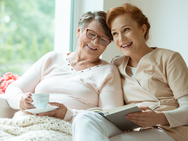 Senior woman and caregiver smiling